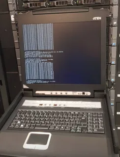 Rack-mounted ATEN KVM console running ping tests in a datacenter