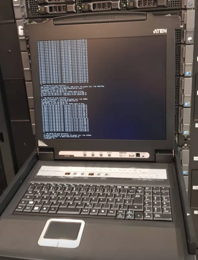 Rack-mounted ATEN KVM console running ping tests in a datacenter