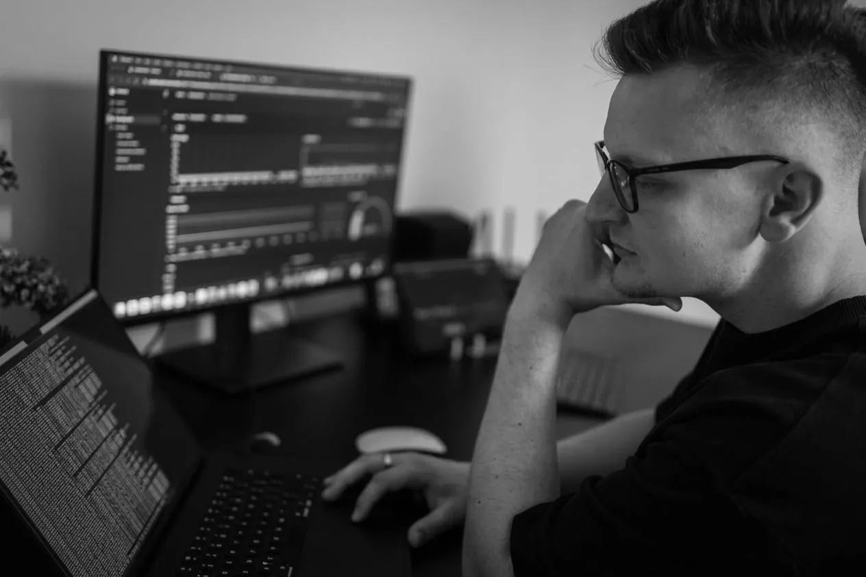 Me at my desk, reading a monitoring dashboard on the monitor with a terminal open on the laptop beside it