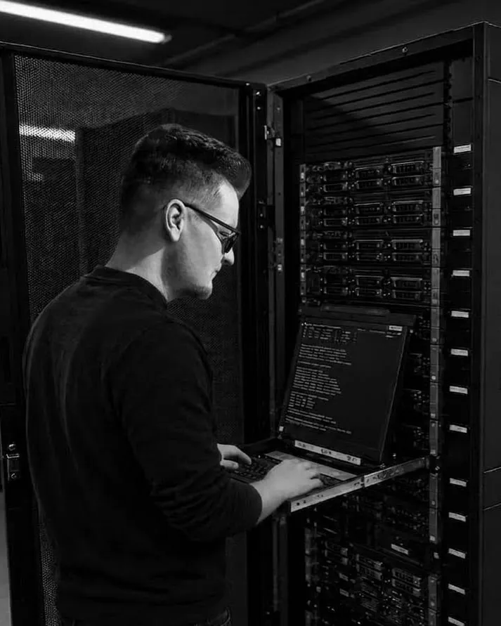 Me at an open server rack in a data centre, typing on the rack's pull-out console