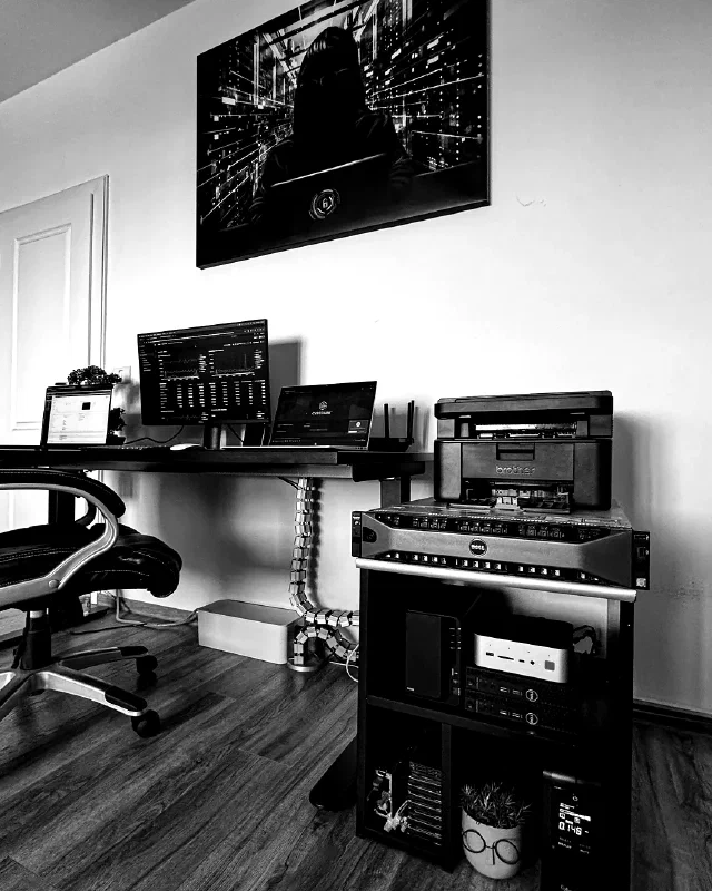 The office corner: a standing desk running monitoring dashboards, and the open rack beside it — R730xd, mini PCs, NAS and UPS
